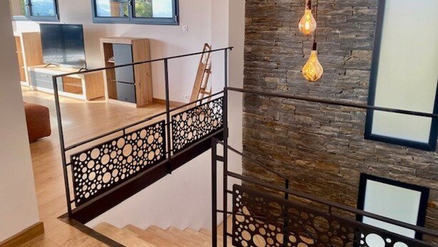 A modern interior with a staircase, a stone wall, and hanging light fixtures. - Luxury chalet for 10 with parking in Font Romeu (Font-Romeu-Odeillo-Via)
