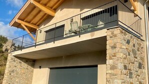 A two-story house with a stone facade, a balcony with metal railings, and a garage door. - Luxury chalet for 10 with parking in Font Romeu (Font-Romeu-Odeillo-Via)