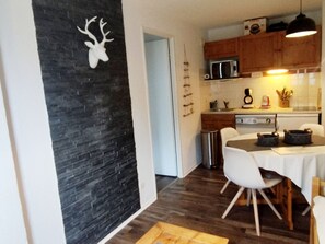 Eine moderne Küche mit einer Steinwand, Holzschränken, einer Mikrowelle und einem Essbereich mit Tisch und Stühlen.