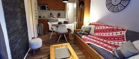 A cozy living room with a sofa, a wooden coffee table, and a dining area with a table and chairs.