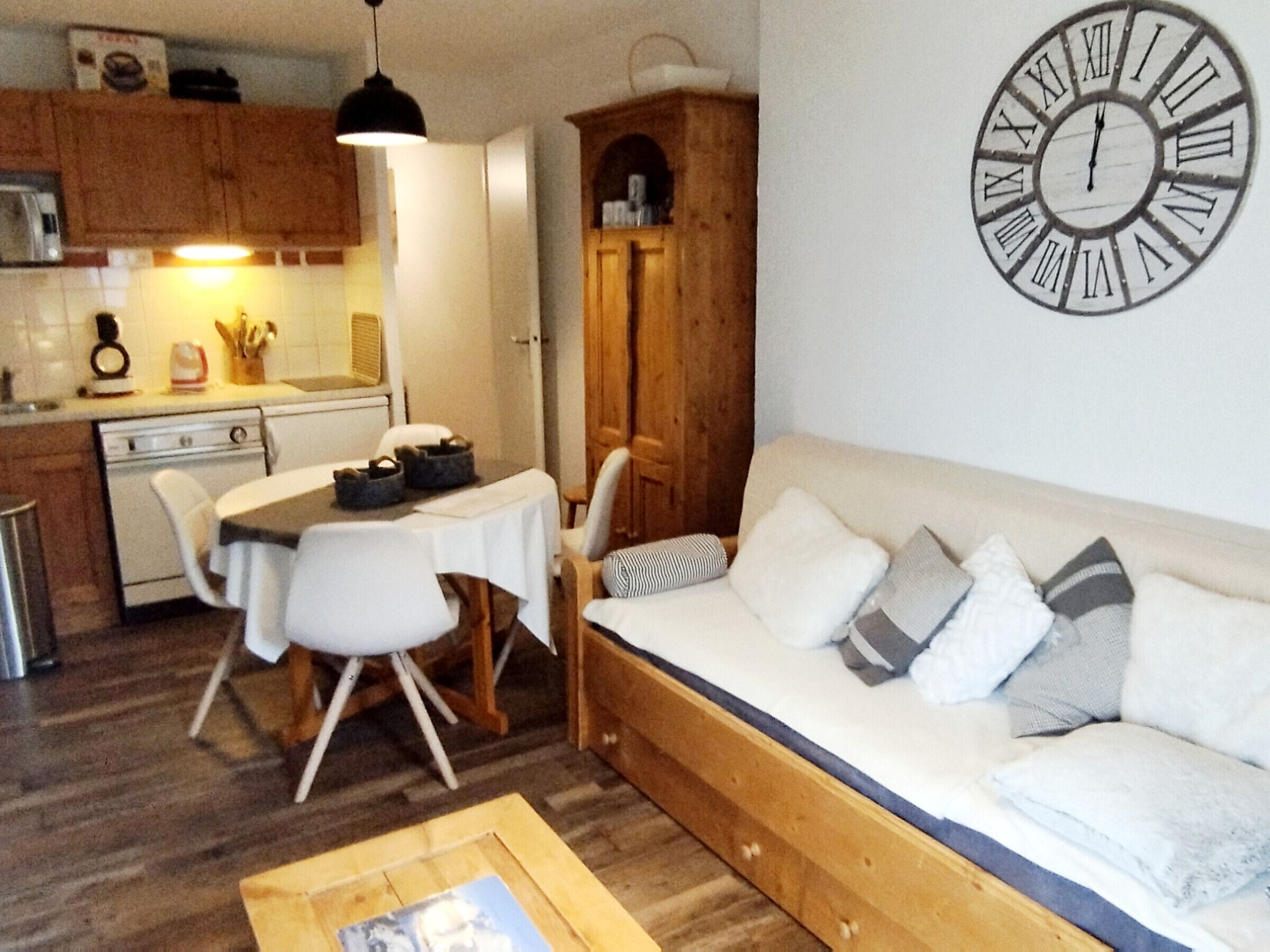 A compact living space with a dining area, a sofa, and a wall clock.
