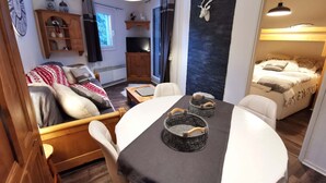 Ein gemütliches Wohnzimmer mit einer Couch, einem Esstisch mit Körben, einem Fernseher und einem Kamin.