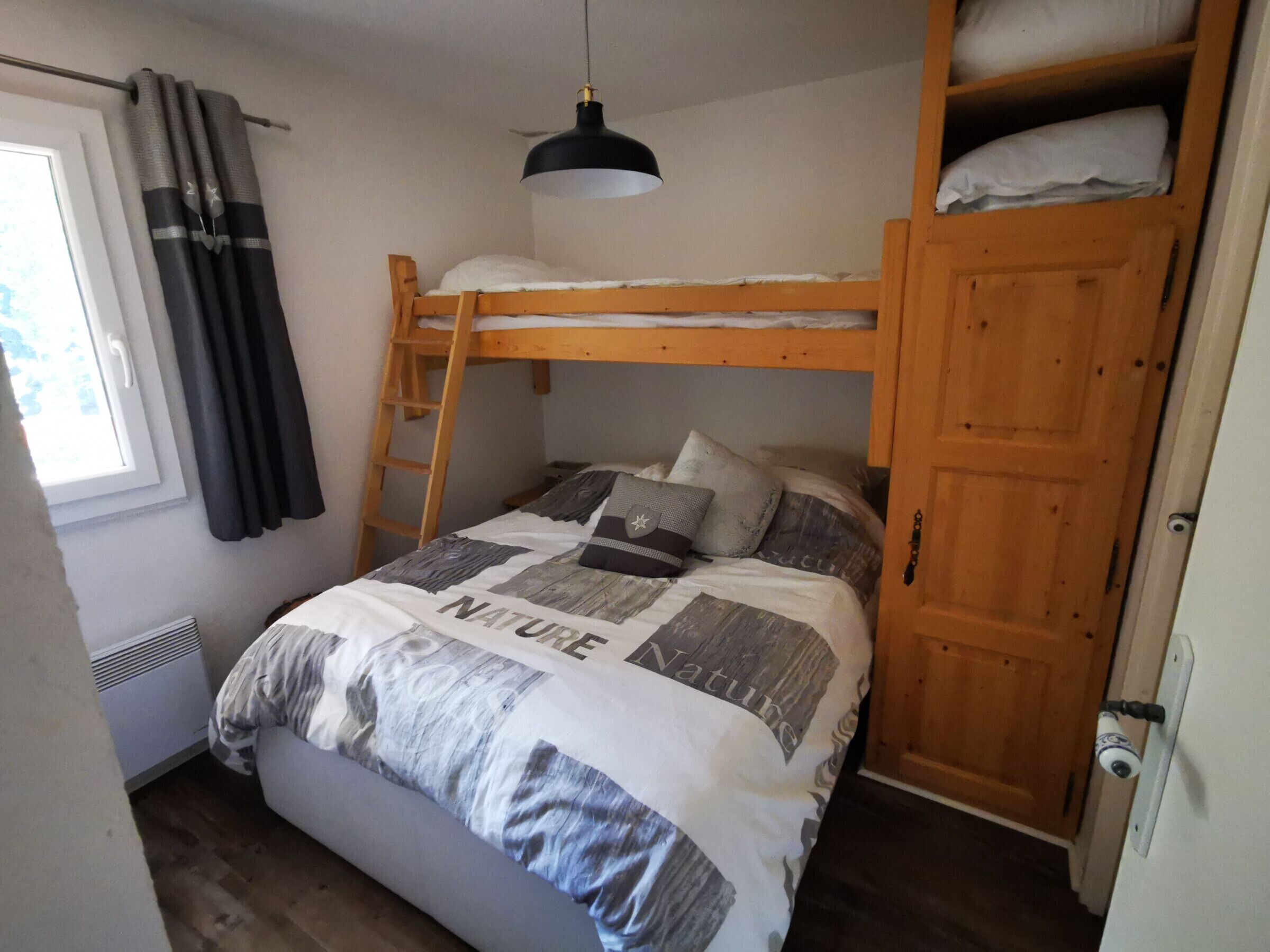 Ein Etagenbett mit Holzleiter, einer Hängelampe und einer Tür mit Blickspion.