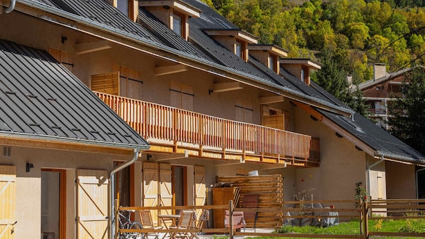 Eine Chalet mit Balkon, Holzh shutters und einem Berg im Hintergrund.
