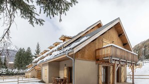 Eine Holzhütte mit Balkon, Essbereich und überdachter Terrasse.