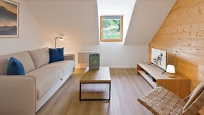 Ein modernes Schlafzimmer im Loftsstil mit schrägen Wänden, einem Holztisch, einer Couch, einem kleinen Tisch und einem Bett.