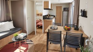 A compact living space with a sofa, a dining table with chairs, a kitchen area, and a small balcony. - Cozy mobile home for 4 with terrace (Granges-Aumontzey-Aumontzey)