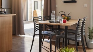 A modern dining area with a wooden table, black chairs, a fruit bowl, and a coffee machine. - Cozy mobile home for 4 with terrace (Granges-Aumontzey-Aumontzey)
