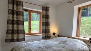 A bedroom with a large bed, two windows, and curtains. - New 3-room apartment with parking and balcony in Valmorel (Valmorel)