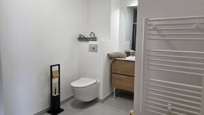 A modern bathroom with a toilet, a wooden vanity, and a towel rack. - Charming T2 Valmorel, balcony, covered parking (Valmorel)