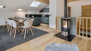 A modern kitchen with a skylight, a dining area with a table set for six, and a wood-burning stove. - Duplex at the slopes with sauna, 5 bedrooms for 12 (Saint-Martin-de-Belleville)
