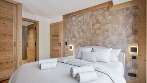 A modern bedroom with a large bed, wooden walls, and built-in lighting. - Duplex at the slopes with sauna, 5 bedrooms for 12 (Saint-Martin-de-Belleville)