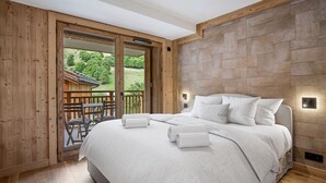 A bedroom with a large bed, wooden walls, and a view of a garden. - Duplex at the slopes with sauna, 5 bedrooms for 12 (Saint-Martin-de-Belleville)