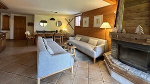 Un salon chaleureux avec une cheminée, un coin repas et une cuisine.