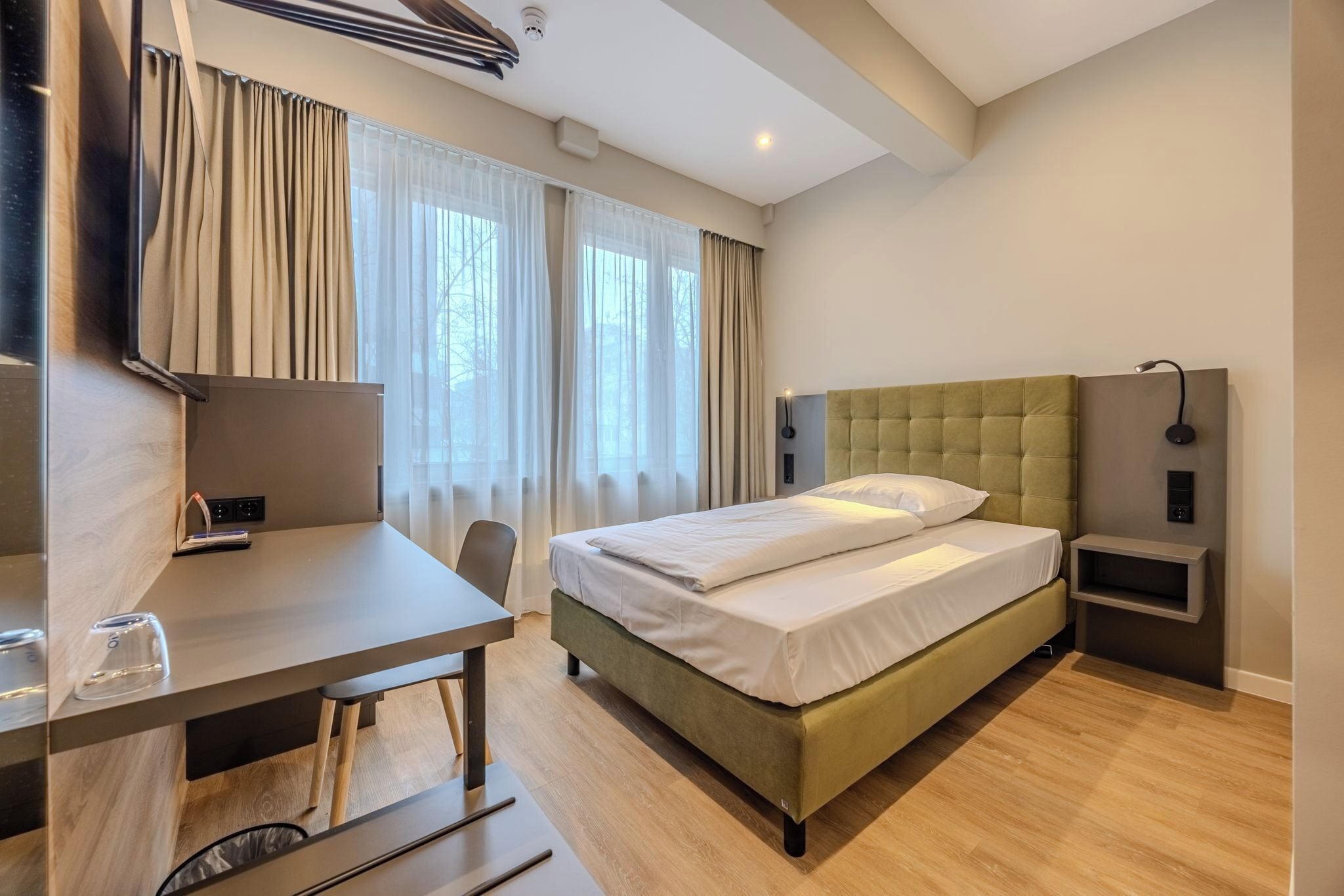 Una habitación de hotel moderna con una cama, un escritorio y una silla.