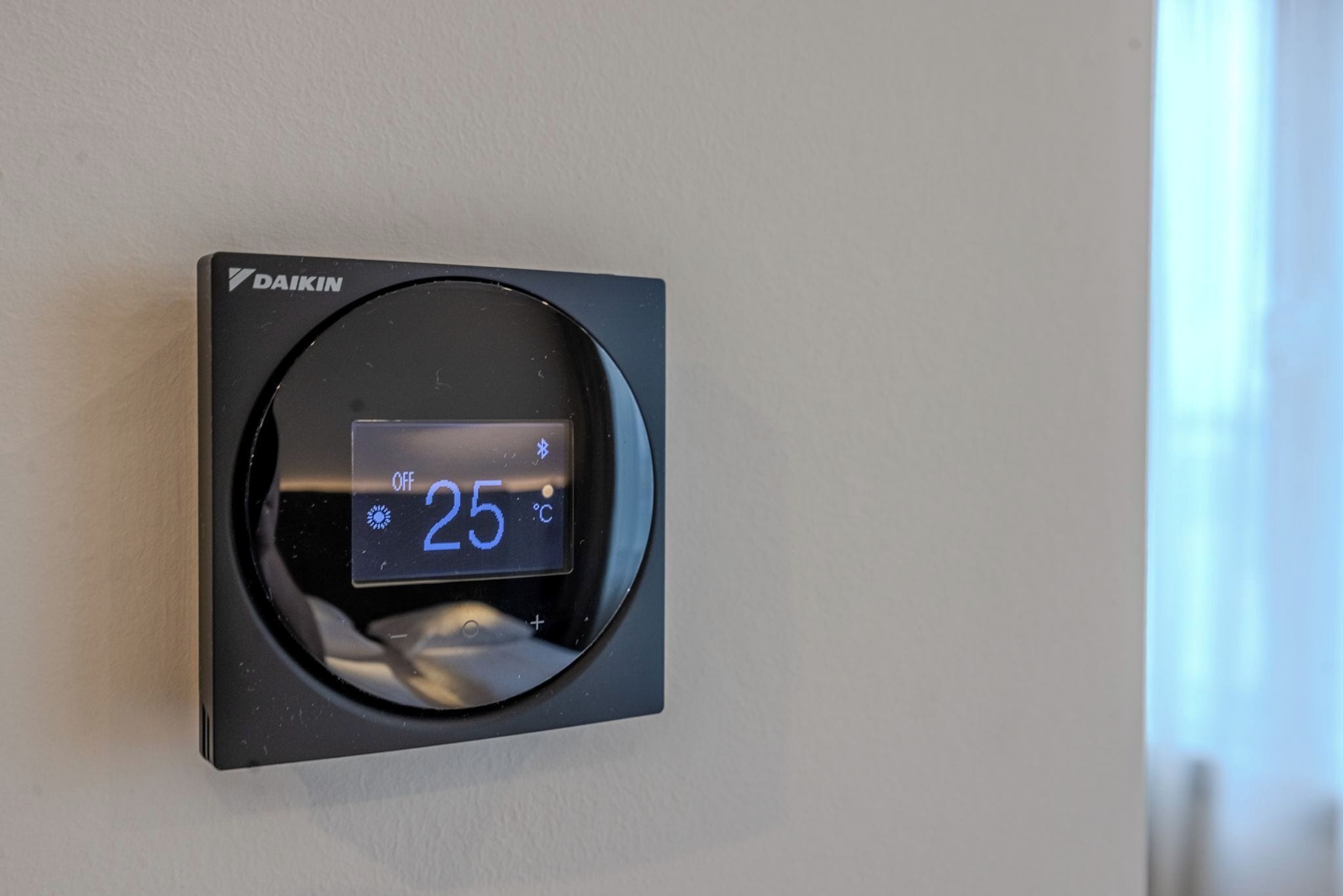 A thermostat with the brand 'DAIKIN' and a temperature reading of 25°C.