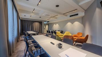 Ein moderner Konferenzraum mit einem langen Tisch, mehreren Stühlen und vielfältigen Sitzgelegenheiten in unterschiedlichen Farben.
