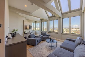 Un salón amplio con techo alto, ventanas grandes y vistas a la ciudad.