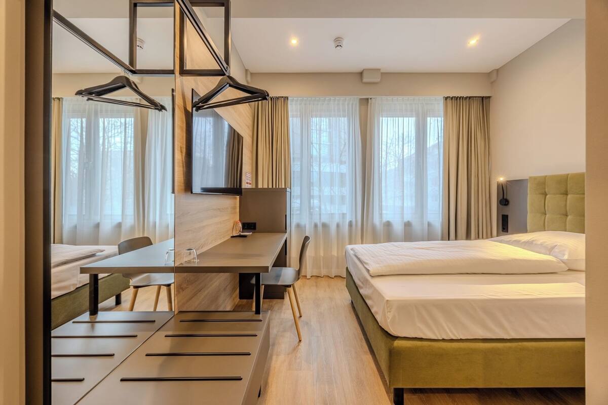 Une chambre d’hôtel moderne, équipée d’un lit, d’un bureau et d’une chaise.