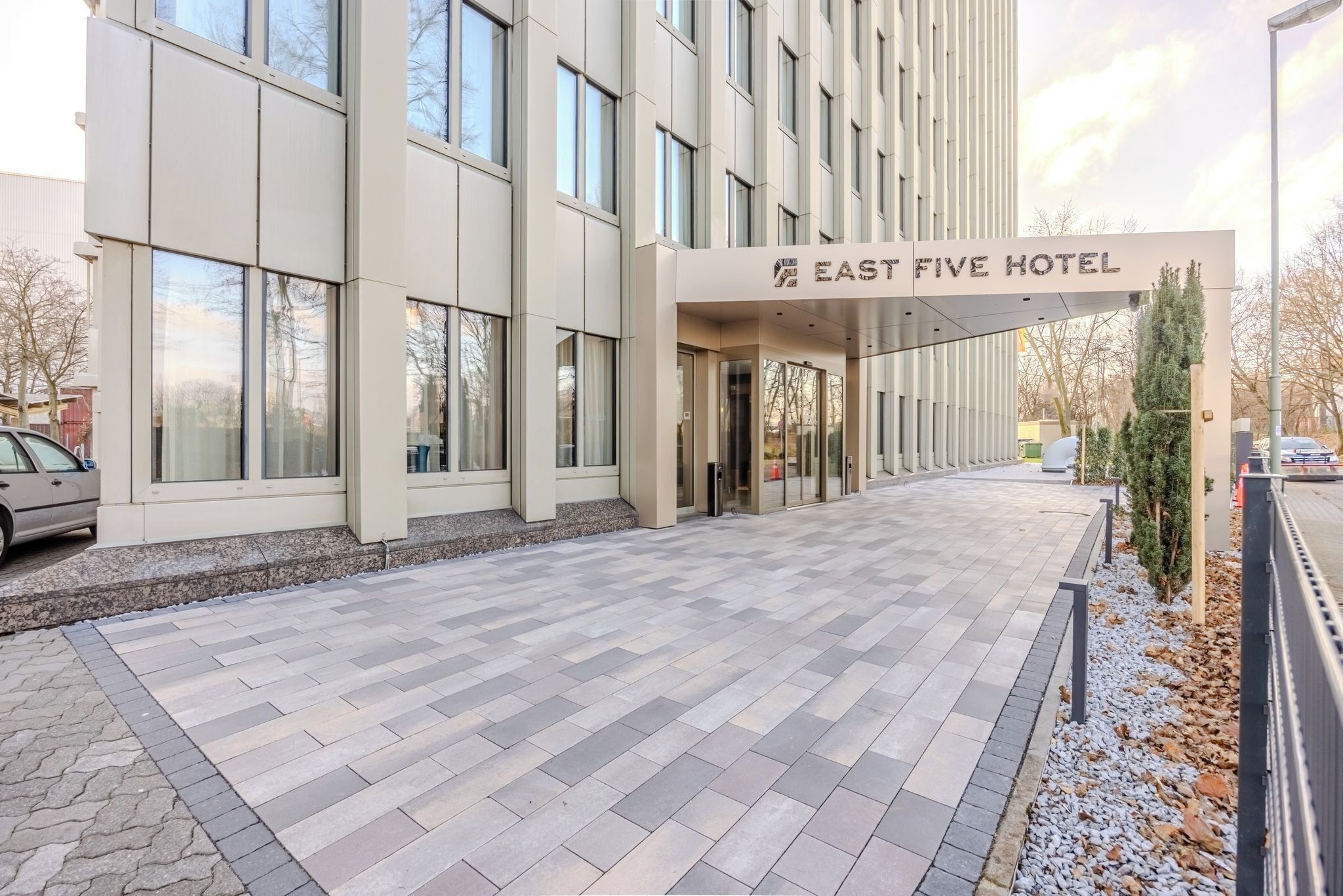 De ingang van Hotel East Five met een betegelde looppad naar de deuren.