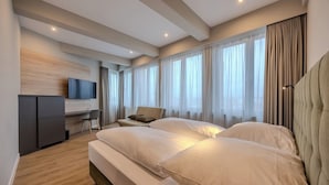 Une chambre d’hôtel moderne, dotée d’un grand lit, d’un bureau et d’une télévision.
