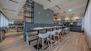 Un restaurant moderne doté d’un bar, de planchers en bois et d’une cuisine située au fond de la salle.