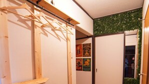 A room with a wooden shoe rack, a green artificial grass area, and a wall with posters. - Route 99 Yumoto (Hakone)