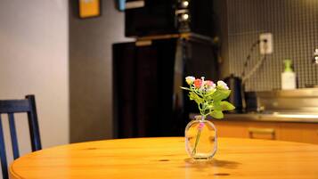Una mesa redonda de madera con un florero de vidrio transparente con flores.
