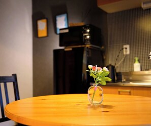 Une table ronde en bois sur laquelle est posé un vase en verre transparent rempli de fleurs.