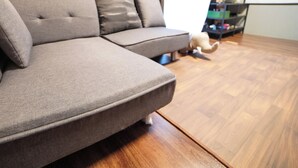 A grey sectional sofa with a wooden floor and a black shelf in the background. - Route 99 Yumoto (Hakone)