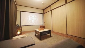 A room with a bed, a small table, a projector screen, and sliding doors. - Route 99 Yumoto (Hakone)