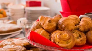 Una mesa de buffet con una variedad de pasteles, incluyendo croissants y otras preparaciones horneadas.