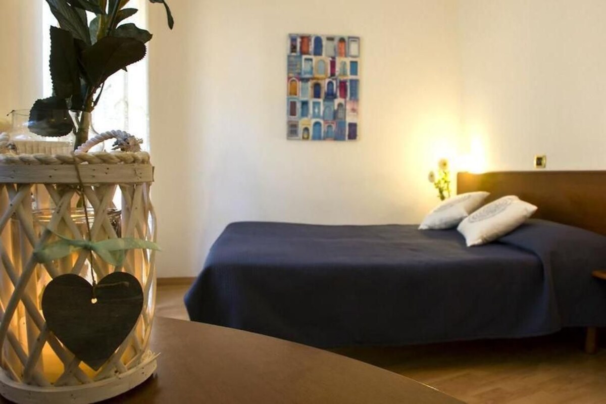 Un dormitori amb un llit, un quadre penjat a la paret i un fanal decoratiu amb un adorn de cor.