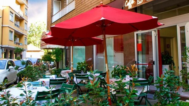 Un café en plein air avec des parasols rouges, des tables et des chaises.