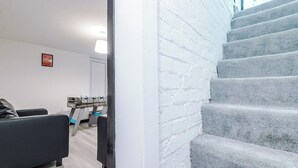 A staircase with a white brick wall and a grey carpeted floor.