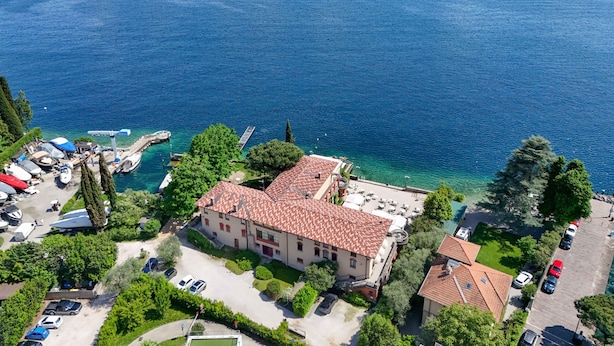 A coastal property with a large building, clear blue waters, and a marina with boats.