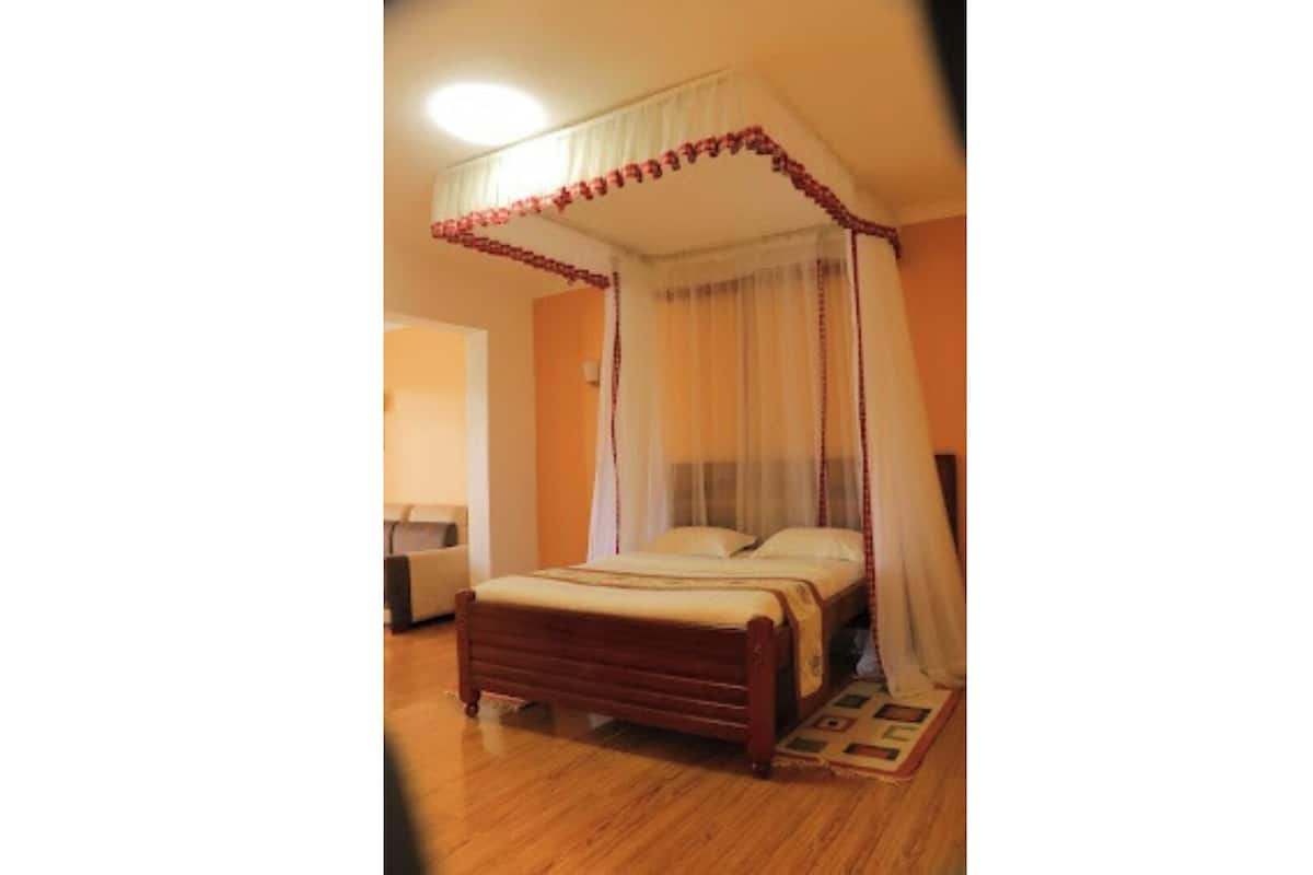 Un dormitorio con una cama con dosel, una mesita de noche y otra mesita auxiliar.