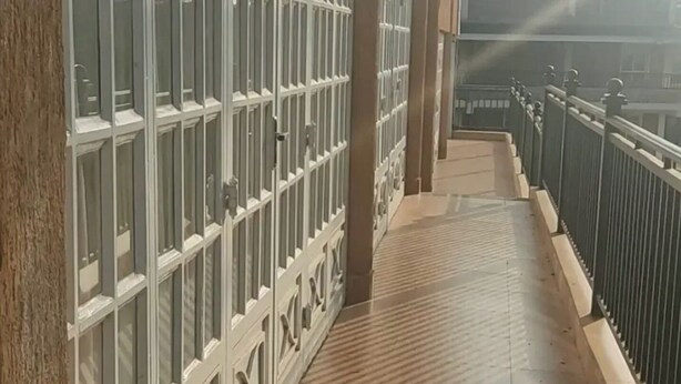 A corridor with a tiled floor and a metal railing on one side. - Fairways Hotel (Narok)