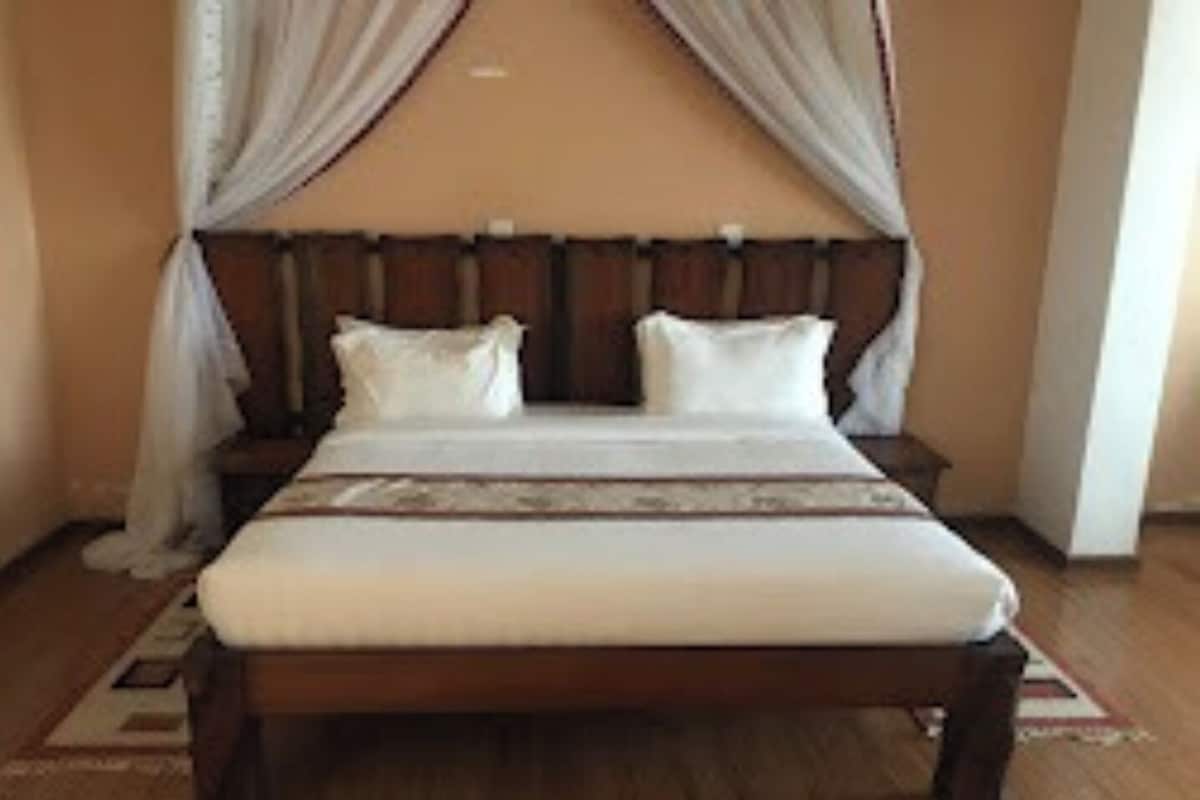 A neatly made bed with a wooden headboard, white bedding, and a decorative pillow.