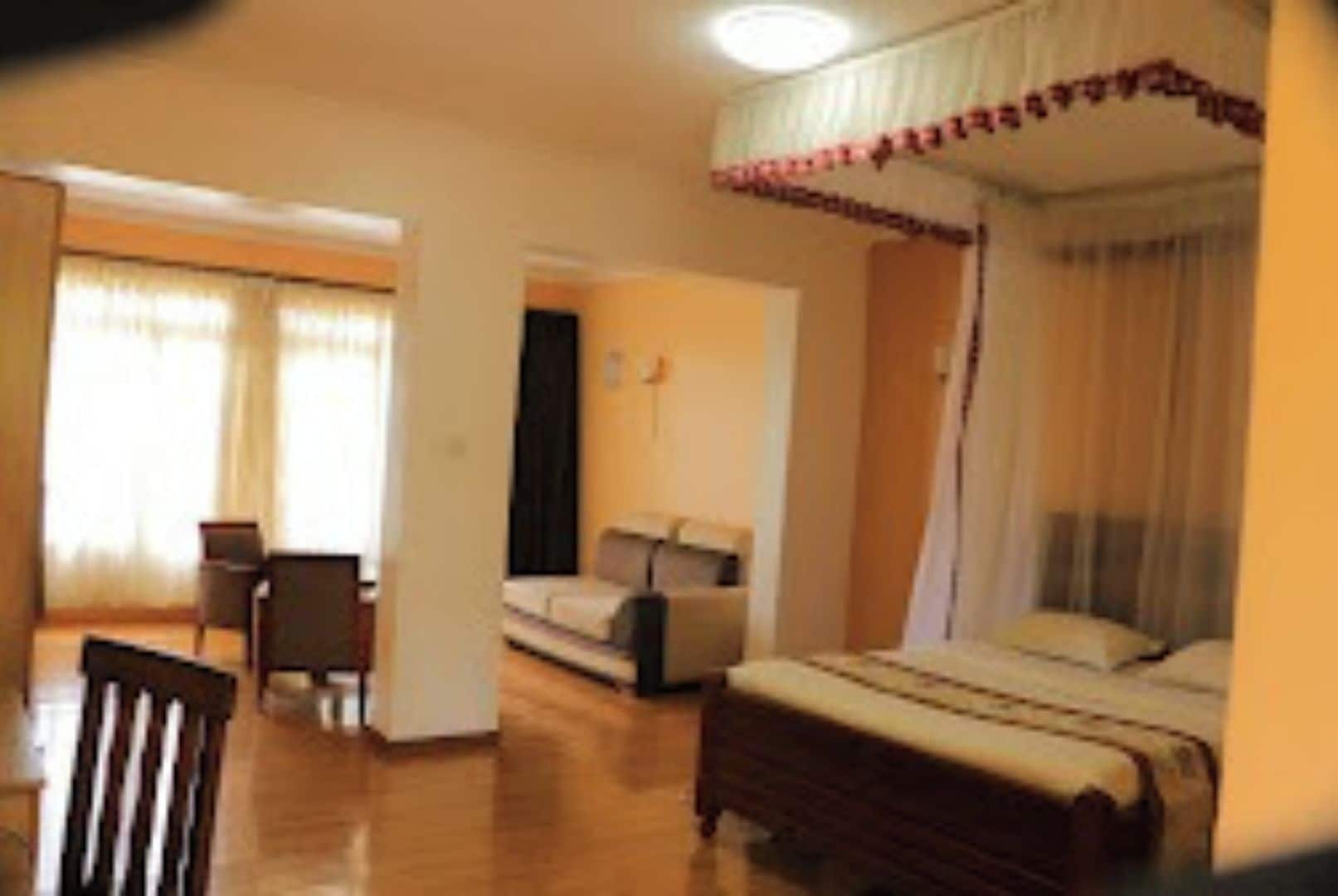 A bedroom with a four-poster bed, a sofa, and a desk.