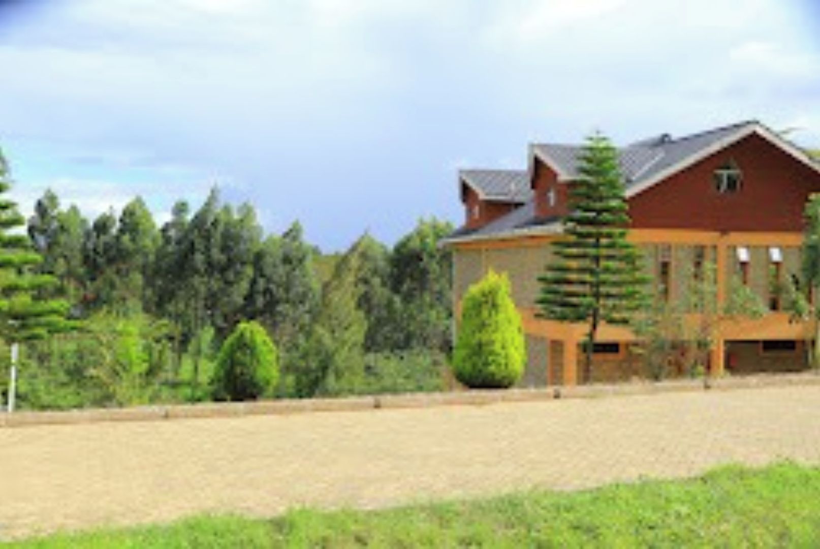 A large house with a red roof, surrounded by a well-maintained lawn and trees.