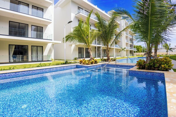 Una piscina al aire libre, sombrillas, tumbonas