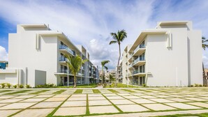 A modern hotel with a central courtyard featuring a geometric pattern of grass and concrete. - Tropical 2BR Retreat - Terrace, BBQ and Pool (Punta Cana)