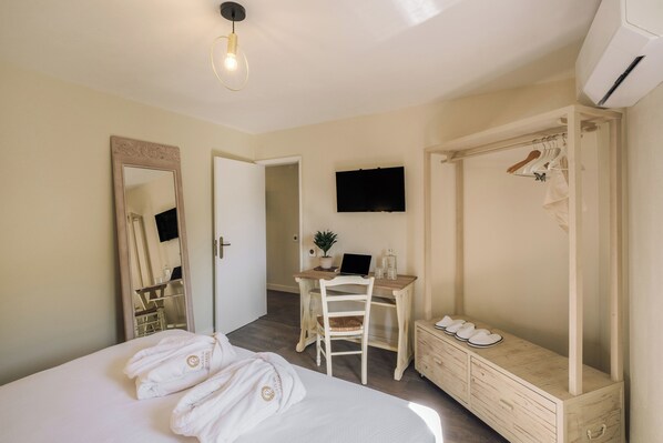 Une chambre d’hôtel comprenant un lit, un bureau, une chaise, une armoire et un téléviseur.