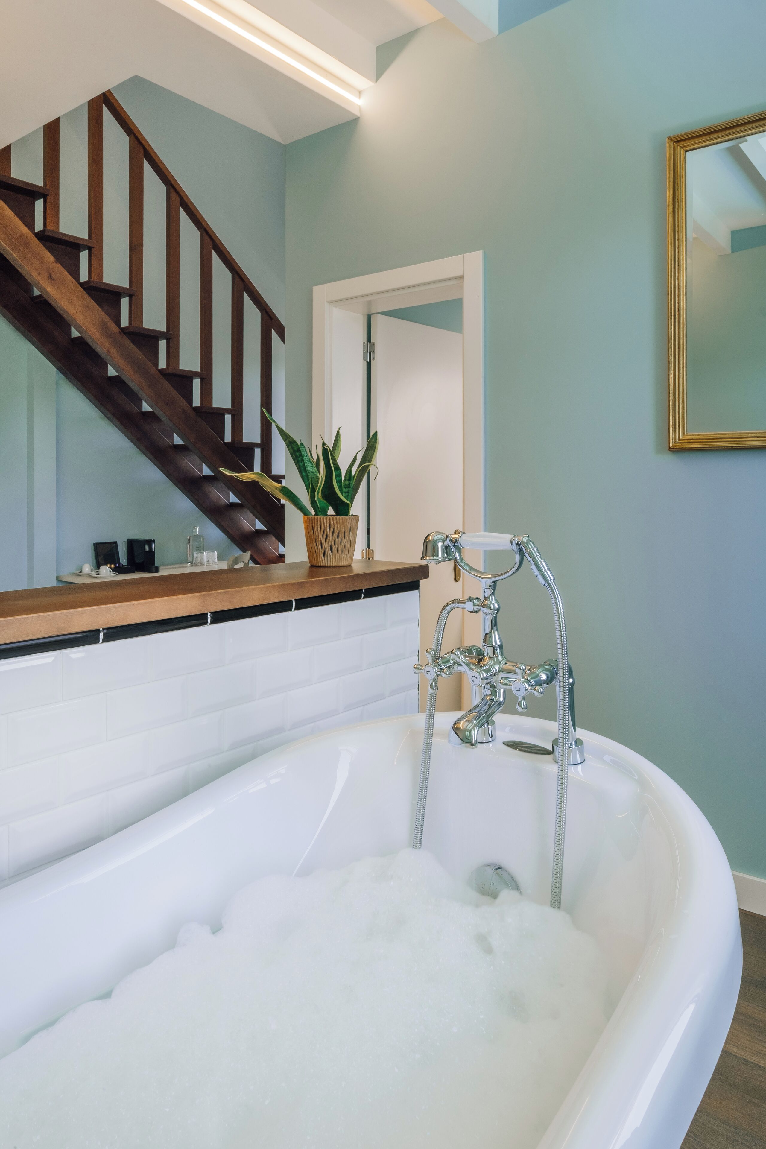 Ein Badezimmer mit einer Badewanne, einer Holztreppe und einer Topfpflanze.