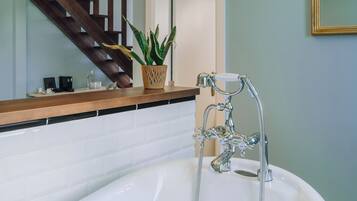 Ein Badezimmer mit einer Badewanne, einer Holztreppe und einer Topfpflanze.