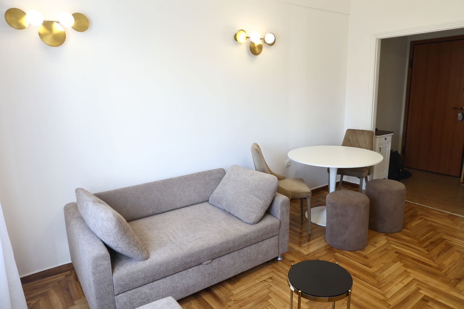A modern living room with a grey sofa, two armchairs, a round coffee table, and a small side table.
