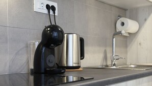A kitchen with a coffee maker, a kettle, and a roll of toilet paper on the counter. - Serene & Stylish Apt Athens – Exarcheia by GHH (Athens)