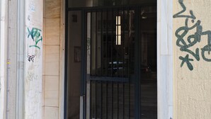 A building entrance with a metal gate, a number sign '81', and some graffiti on the wall. - Serene & Stylish Apt Athens – Exarcheia by GHH (Athens)