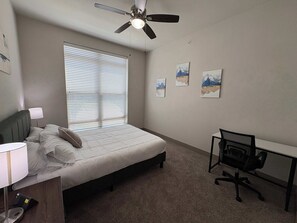 A bedroom with a bed, a desk, a chair, a ceiling fan, and artwork on the wall. - Relax at Cityline I Premium 2BR in Dallas (Playa del Carmen)